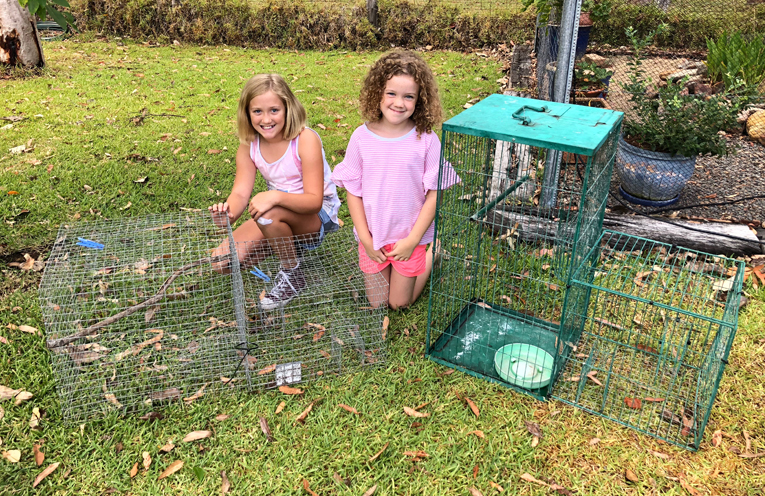 Hannah and Ava Ryder with the two cages their family own to trap Myna birds.